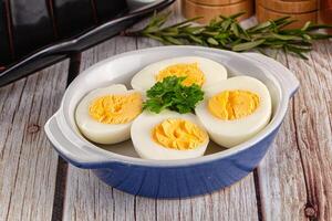 Hard boiled eggs in a bowl on a wooden table photo