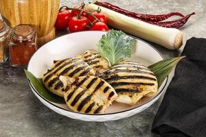 A plate of grilled chicken and vegetables on a table photo