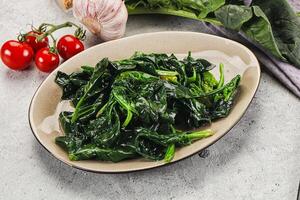 Spinach with garlic and tomatoes on a plate photo