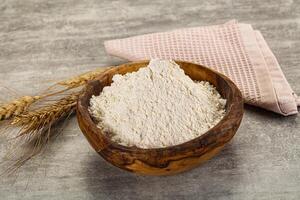 A bowl of flour and a spoon next to a wheat ear photo