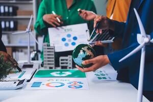 Business people working together on a table with a globe and wind turbines photo