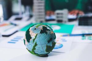 A green globe on a table with a business man in the background photo