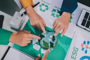 People pointing at a green globe with recycling symbols photo