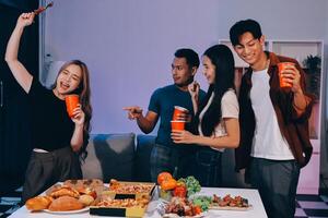 A group of people standing around a table with food photo
