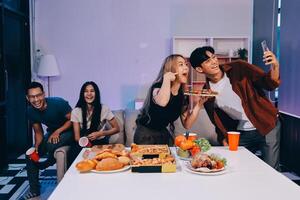 A group of people sitting around a table with pizza and drinks photo