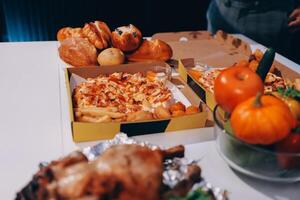A table with two boxes of pizza and other food photo