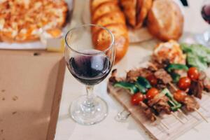 A table with a glass of wine and food photo