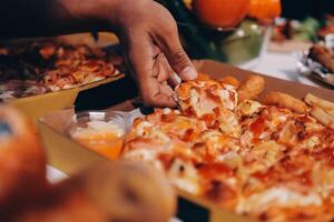 A person taking a piece of pizza from a box photo