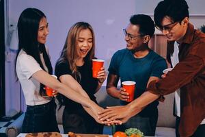 A group of friends holding hands while standing around a table with food photo