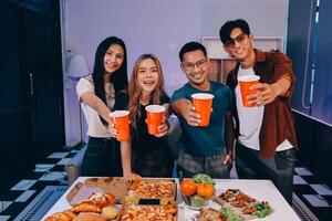Four friends holding drinks and food at a table photo