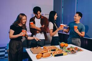 A group of people standing around a table with food photo
