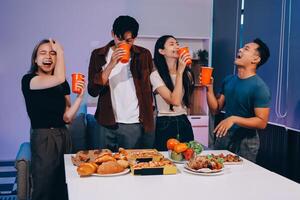 Four people standing around a table with food photo