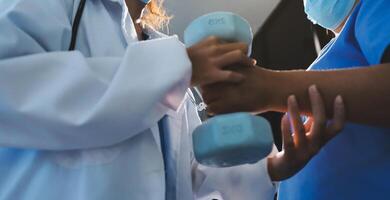 A doctor is holding a dumbbell while another person is wearing a mask photo