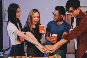 A group of friends holding hands while standing around a table with food photo