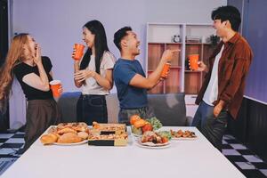 Four people standing around a table with food photo