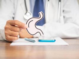 Doctor holding a stomach shape symbol while sitting at the desk photo