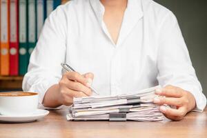Close-up of businessman signing a lease contract or agreement while sitting at the table in the office photo