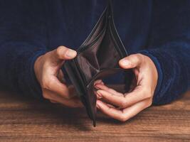 Close-up of hands opens an empty wallet while sitting at the table photo