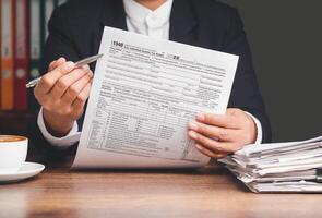 Businessman hand holding a cup of coffee and reading a report while sitting at the table photo