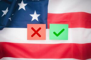Two paper with a green checkmark and a red cross on the American flag background. Top view. photo