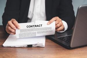 Close-up of businessman in a suit tearing up a contract while sitting at the table photo