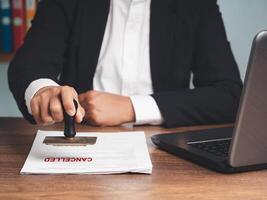 Businessman in a suit stamped for canceled documents while sitting at the table photo
