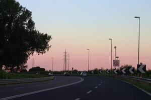 un sereno crepúsculo la carretera con un rotonda y poder líneas foto