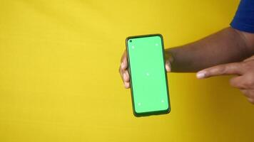 en portant une téléphone intelligent avec une vert écran contre une brillant Contexte video