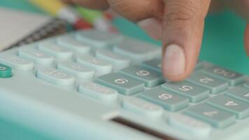 A person calculates numbers on a handheld calculator at a desk video