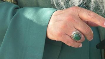 Elegant hand adorned with a green gemstone ring during a gathering video