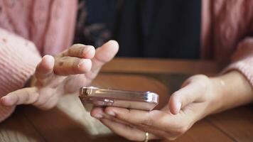 Person using smartphone at a wooden table in a casual setting video