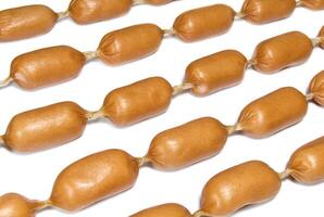 Chains of sausages or frankfurter laid out in row on a white surface photo