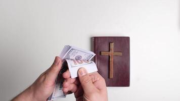 Counting one hundred dollar bills with bible and cross in background video