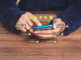 Close-up of hands using a smartphone gives the five-star icon a rating of very impressed for service while sitting at the table photo
