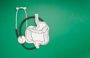 Top view of a stethoscope and large intestine symbol made on a green background. Space for text. photo