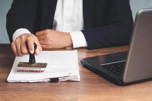 Close-up of businessman in a suit stamped for approved documents while sitting at the table photo