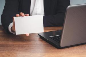 Close-up of hand a businessman in a suit holding a blank white paper while sitting at the table in the office photo