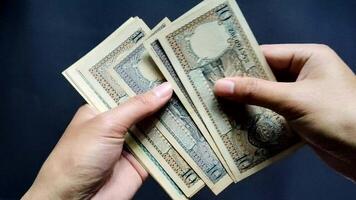 A man shows a handful of old rupiah money, ranging from Rp. 10 to Rp. 500 rupiah. Concept close up view and isolated on a black background video
