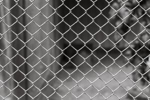 Close-up view of chain link fence with blurred background showcasing an urban environment and a sense of confinement photo