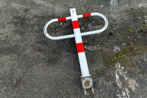 Broken parking barrier laying on the ground with red and white stripes in an urban area on a cloudy day photo