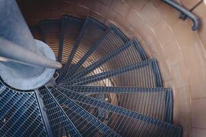 Spiral staircase with metal steps and a circular design captured from a high angle at sunset photo