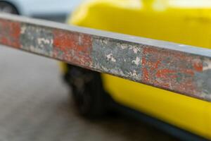 Barrier in focus with yellow vehicle in background during daylight on city street photo