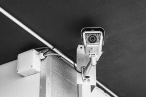 Security camera mounted on wall in indoor space focused on surveillance and monitoring activities photo