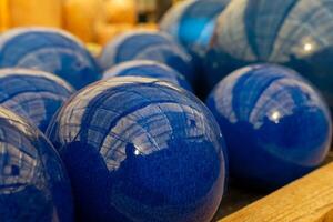 Vibrant blue decorative spheres arranged on a wooden surface with reflections from overhead lights photo