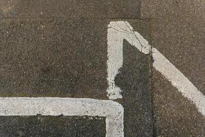 White paint marking on pavement forming an angular design in an urban environment during daylight photo