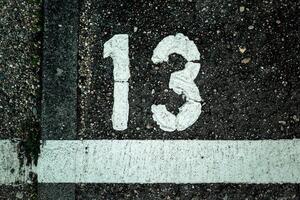 Number 13 marked on a weathered pavement in an urban area showing signs of age and wear photo