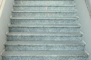 Steps made of polished granite leading up to a well-lit interior in a modern building during daylight hours in an urban setting photo