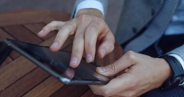 A businessman uses a tablet at an outdoor cafe, highlighting modern technology and connectivity video