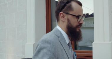 An Elegant Man Dressed in a Smart Suit is Walking Near a Window, Showcasing His Style video