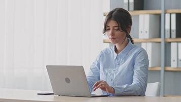 A young woman feeling exhausted an online tutoring session from her home office. She appears deep in thought while working on her laptop, surrounded by a tidy environment. video